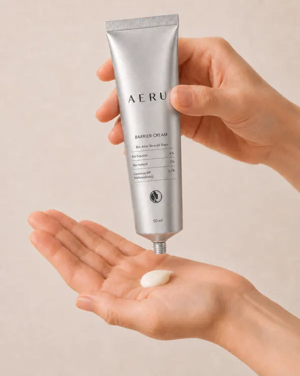 Eine Hand drückt einen Tupfer AERU Barrier Creme aus der Tube