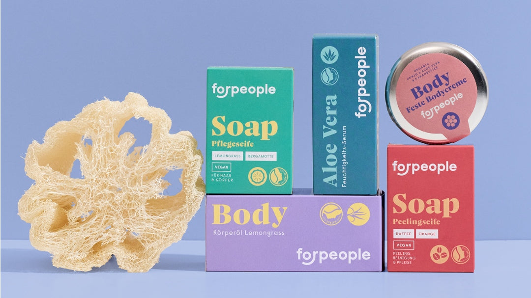 Seifen, Aloe Vera Serum, Körperöl und feste Körperbutter von forpeople neben einem Luffaschwamm